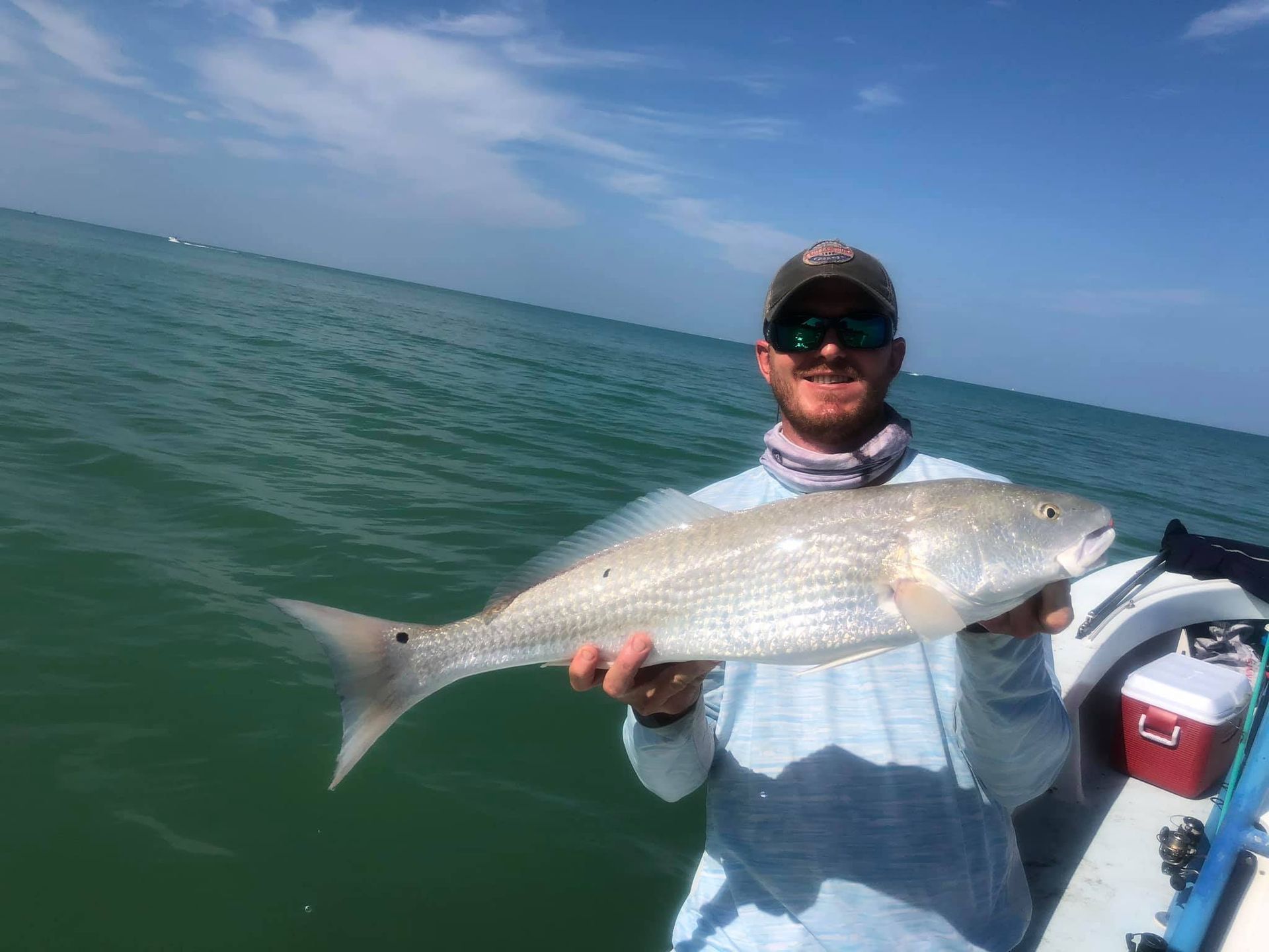 A man is holding a large fish on a boat in the ocean.