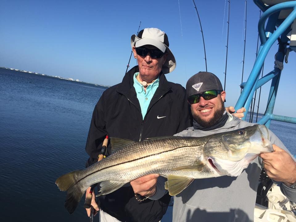Two men are holding a large fish on a boat.