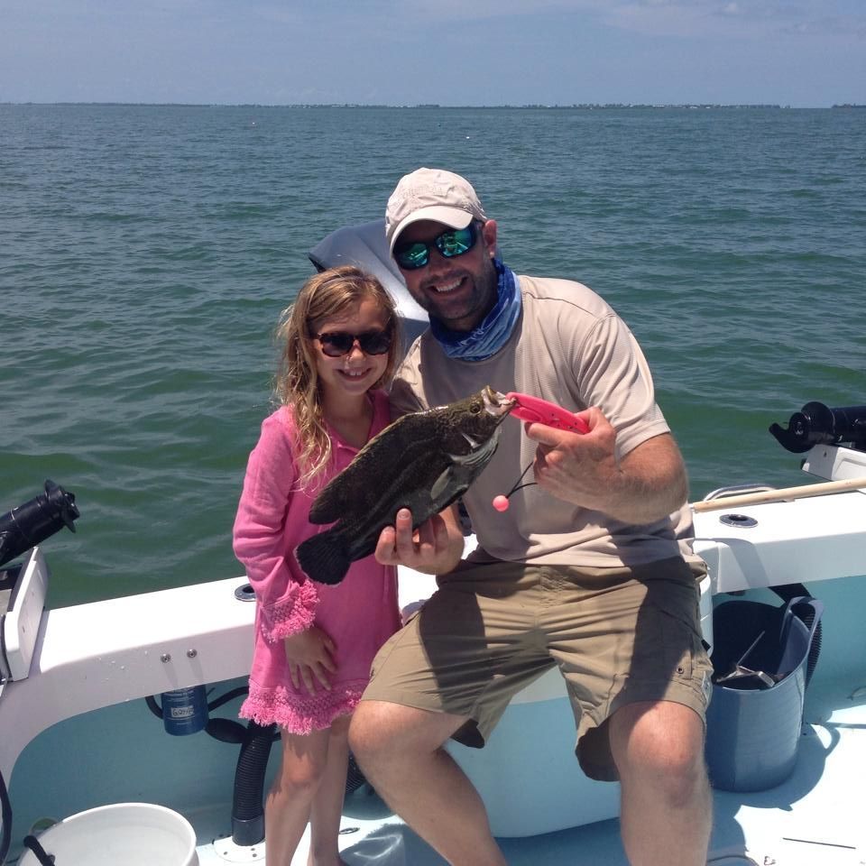 A man and a little girl on a boat holding a fish
