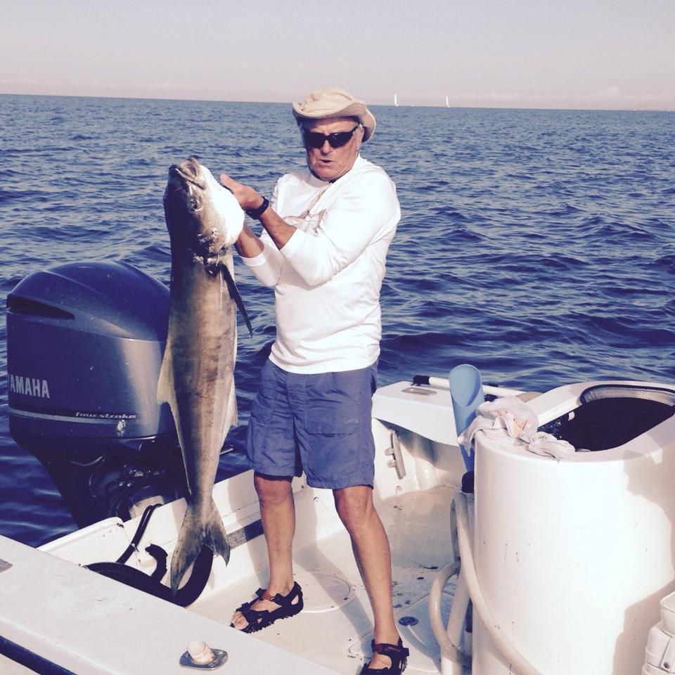 A man standing on a boat holding a large fish
