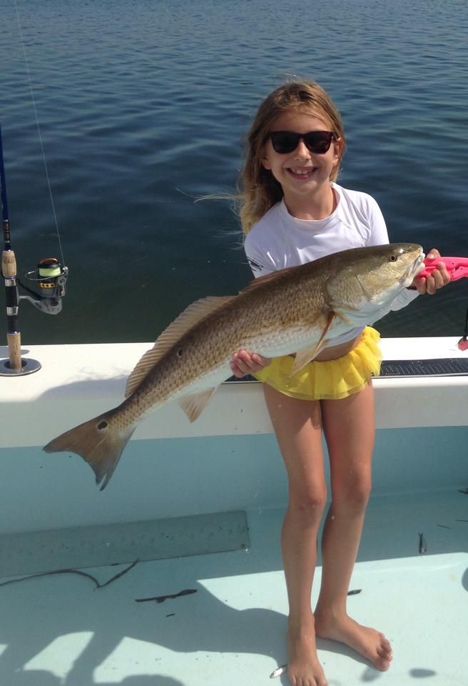 A little girl is holding a large fish on a boat