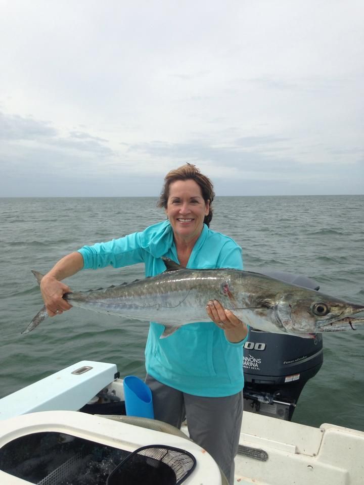A woman is holding a large fish on a boat in the ocean.