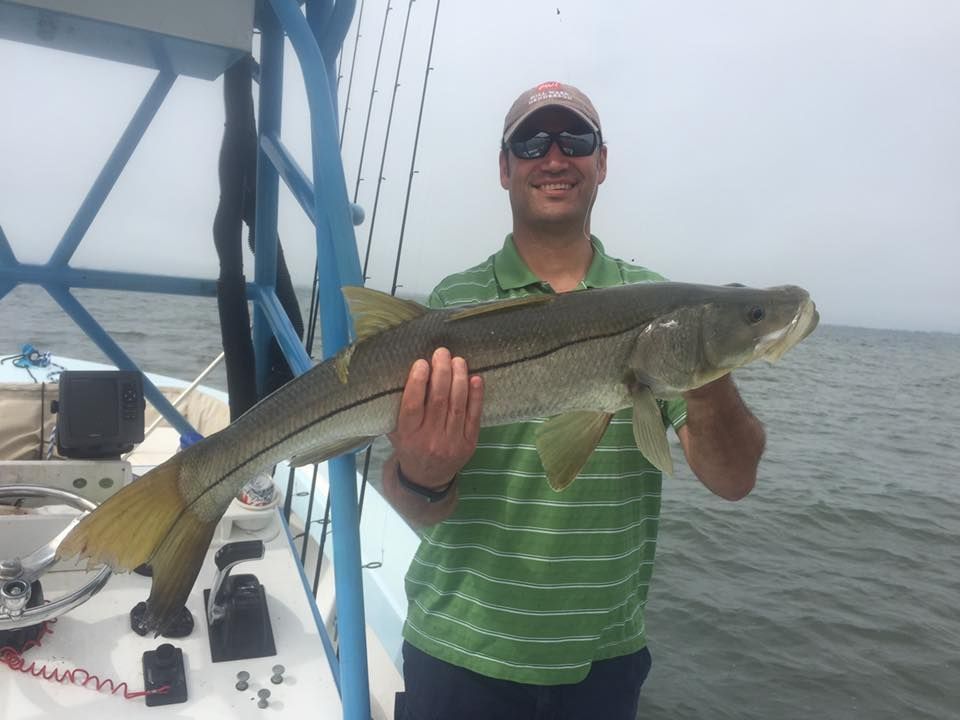 A man is holding a large fish on a boat.