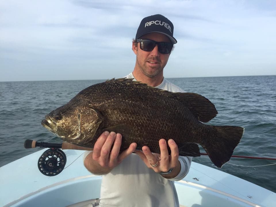 A man is holding a large fish in his hands on a boat