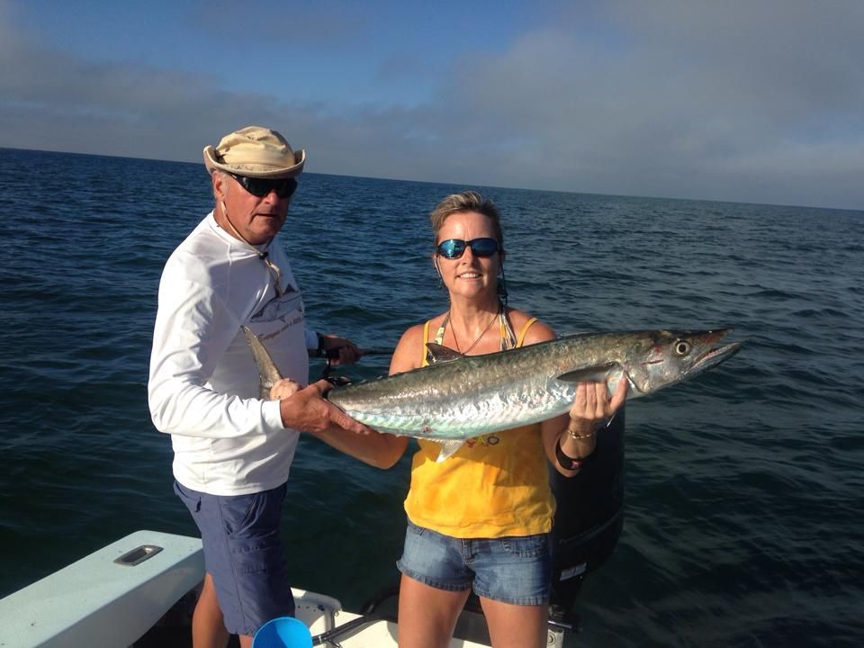 A man and a woman on a boat holding a large fish