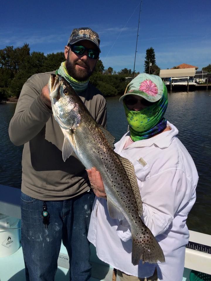 A man and a woman are holding a large fish on a boat.