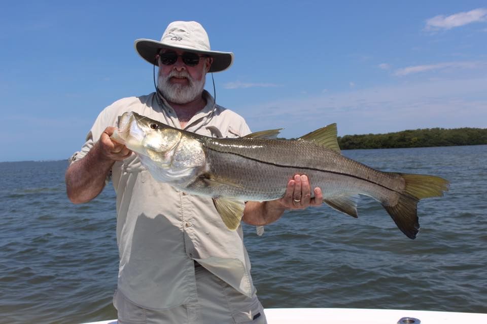 A man is holding a large fish in his hands on a boat.