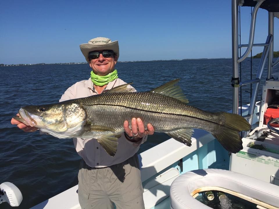A man is holding a large fish on a boat.