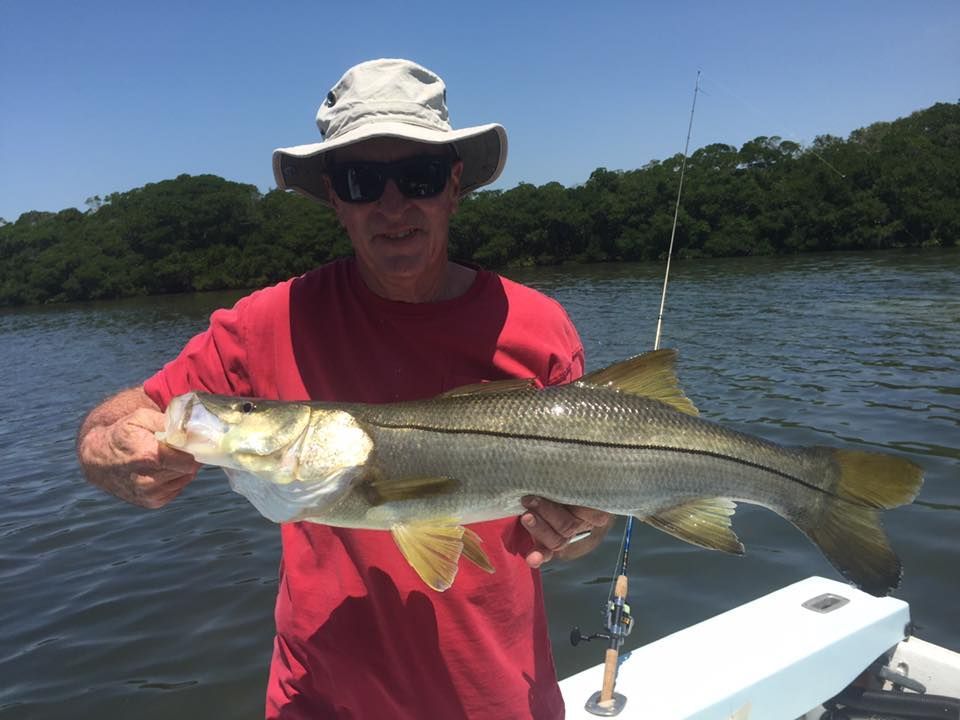 A man is holding a large fish on a boat in the water.