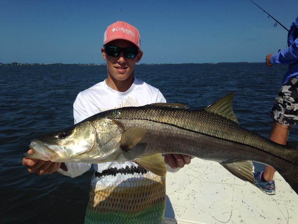 A man in a pink hat is holding a large fish