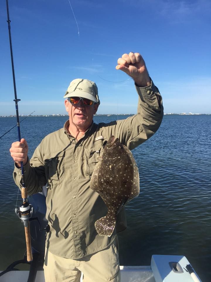 A man is holding a fishing rod and a fish in his hand.