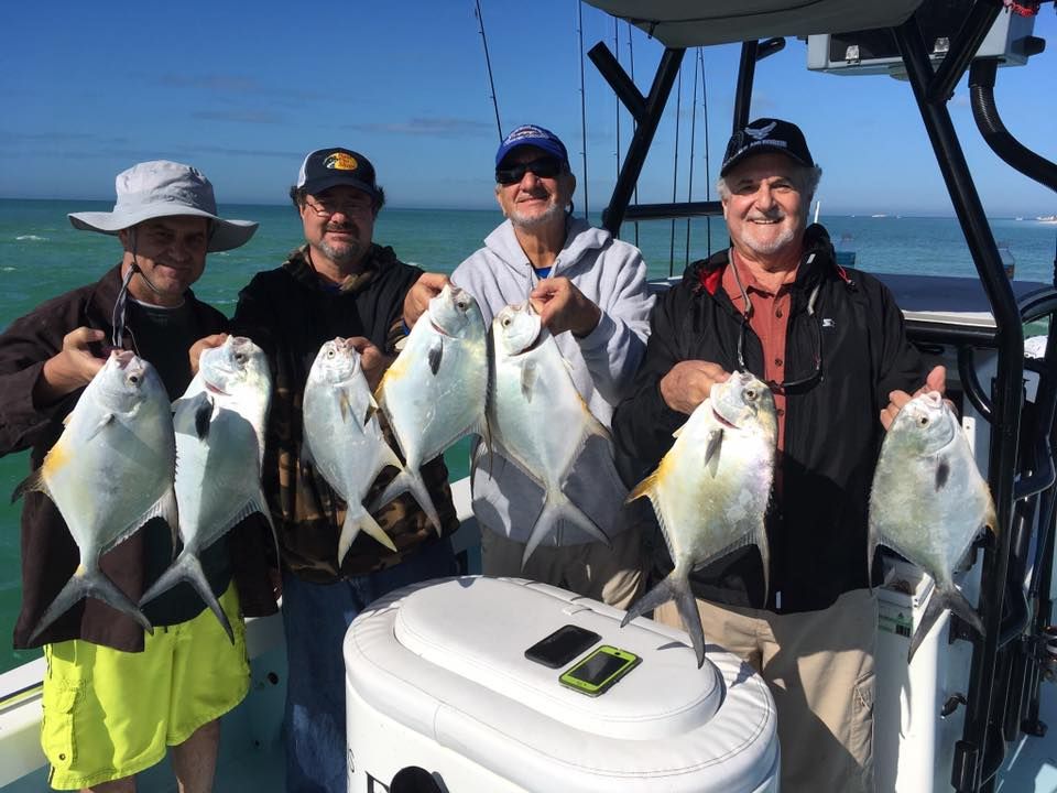 A group of men are standing on a boat holding fish.