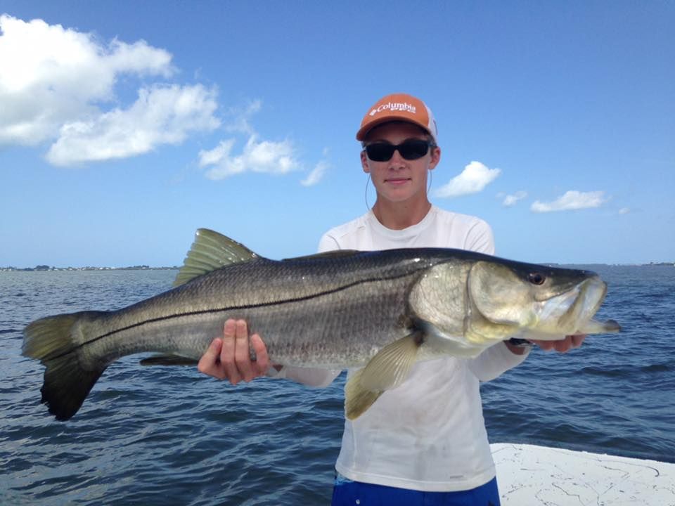 A man is holding a large fish in his hands on a boat.