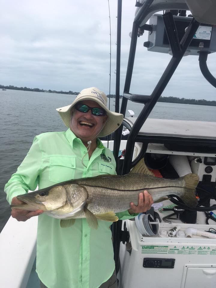 A woman is holding a large fish on a boat