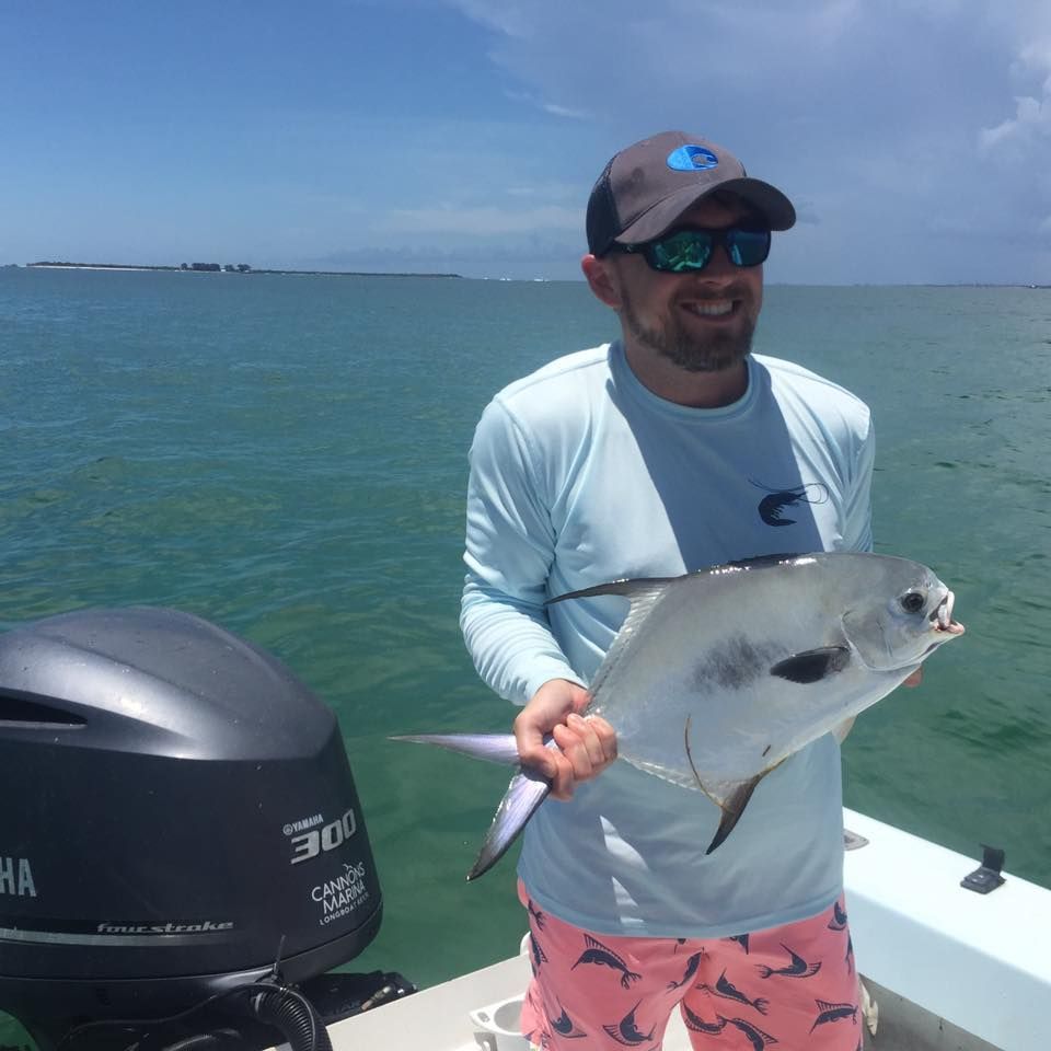 A man holding a fish in front of a yamaha motor