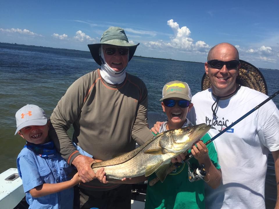 A group of people are standing on a boat holding a large fish.