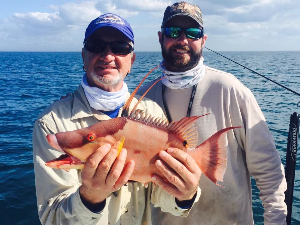 Two men on a boat holding a fish in their hands