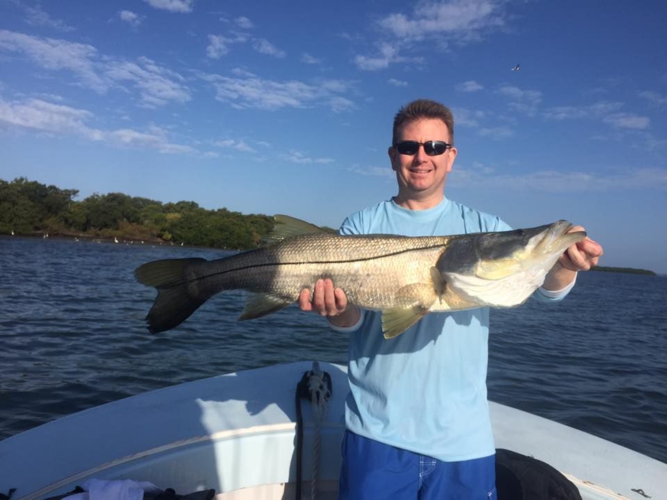A man is standing on a boat holding a large fish.