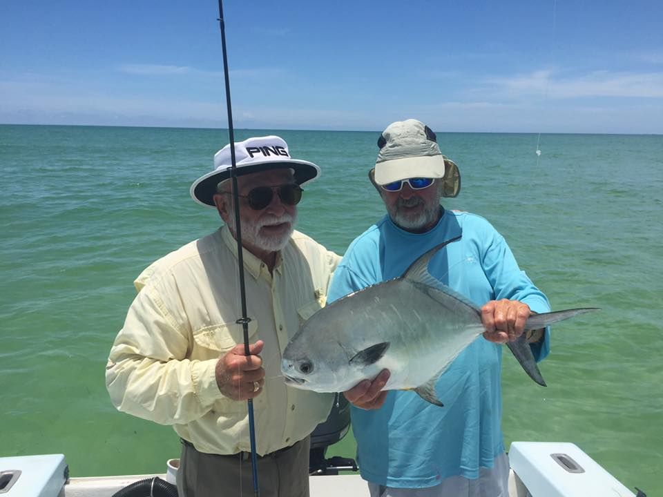 Two men are standing on a boat holding a fish.