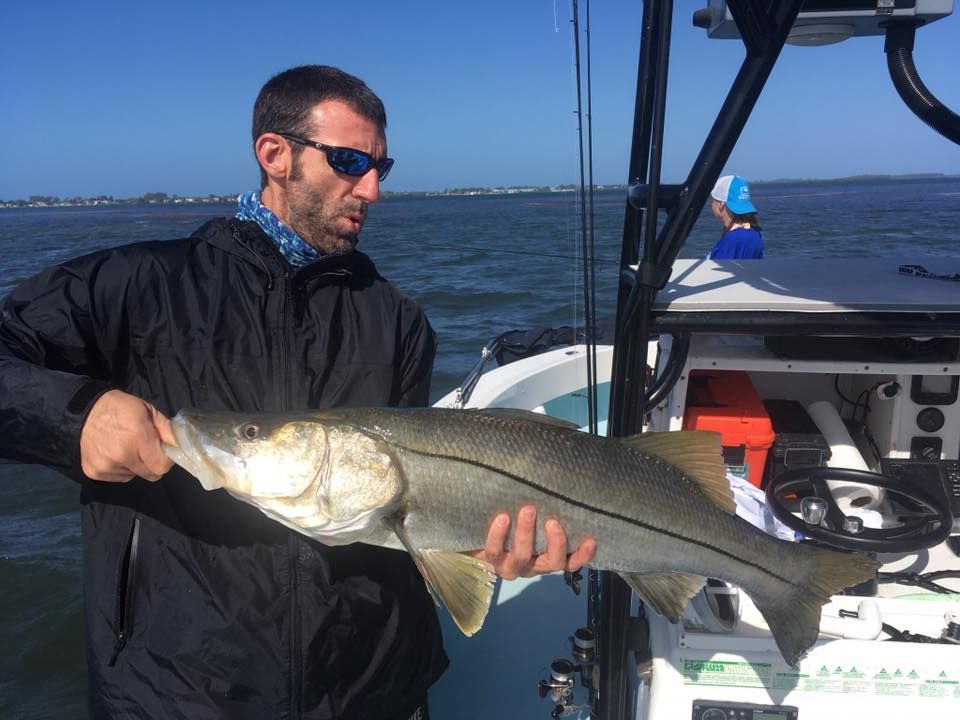 A man is holding a large fish on a boat.