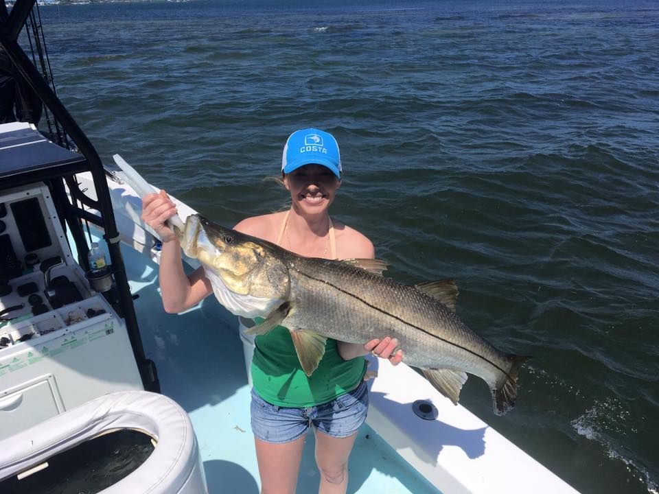 A woman is holding a large fish on a boat.