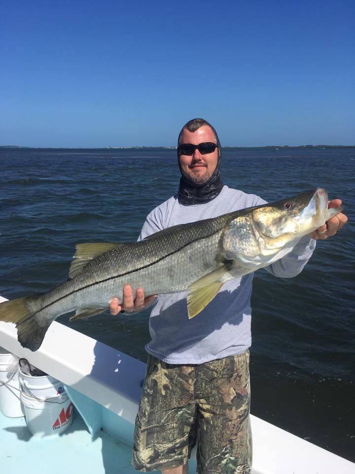 A man is holding a large fish on a boat.