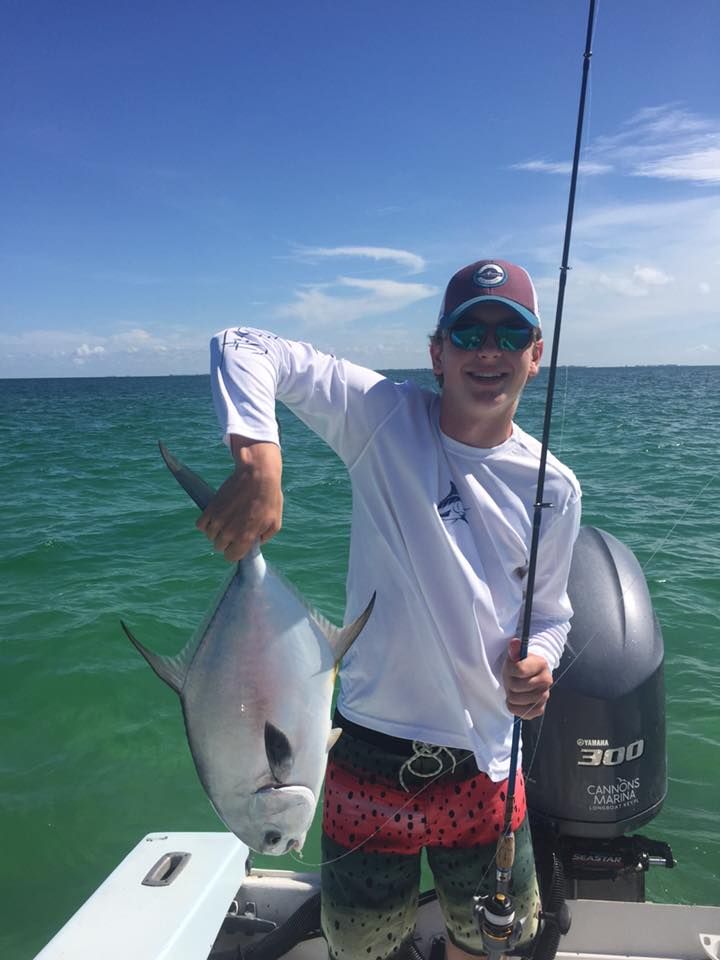 A man is holding a large fish on a boat in the ocean.