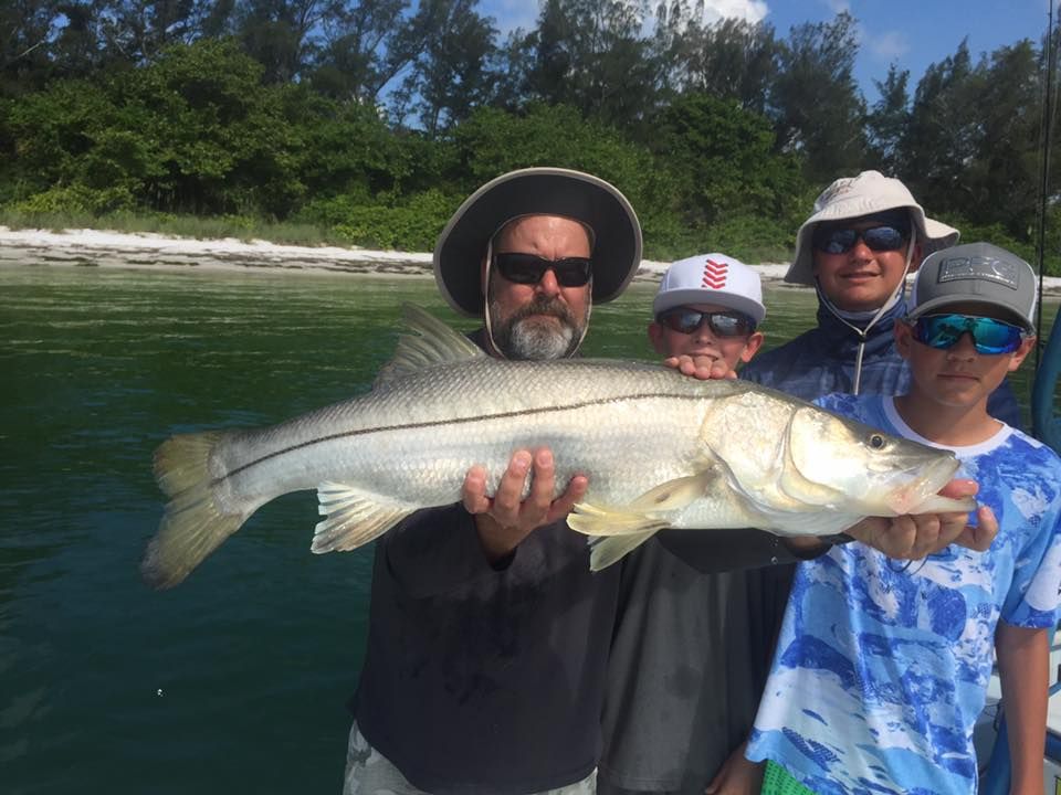 A man and two boys are holding a large fish in their hands.