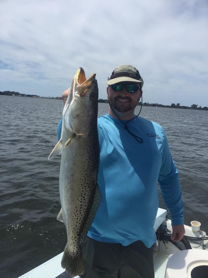A man is holding a large fish on a boat.