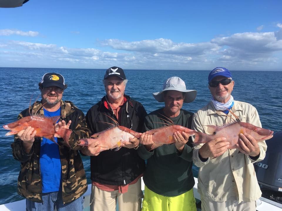 A group of men are standing on a boat holding fish.