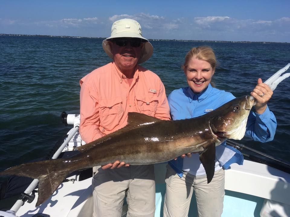 A man and a woman are holding a large fish on a boat.