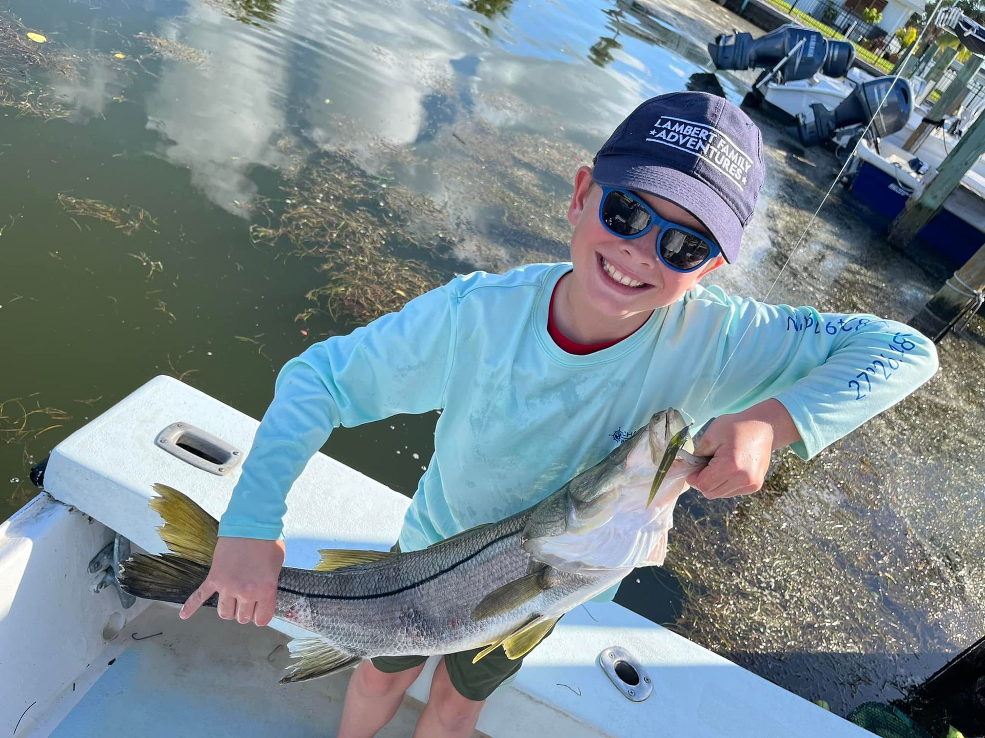 A young boy is holding a large fish on a boat.