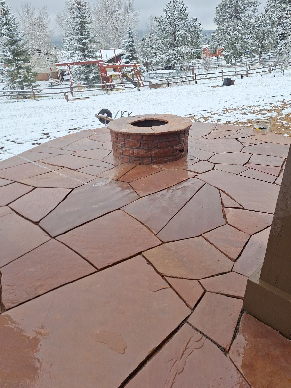 A fire pit is sitting on a patio in the snow.