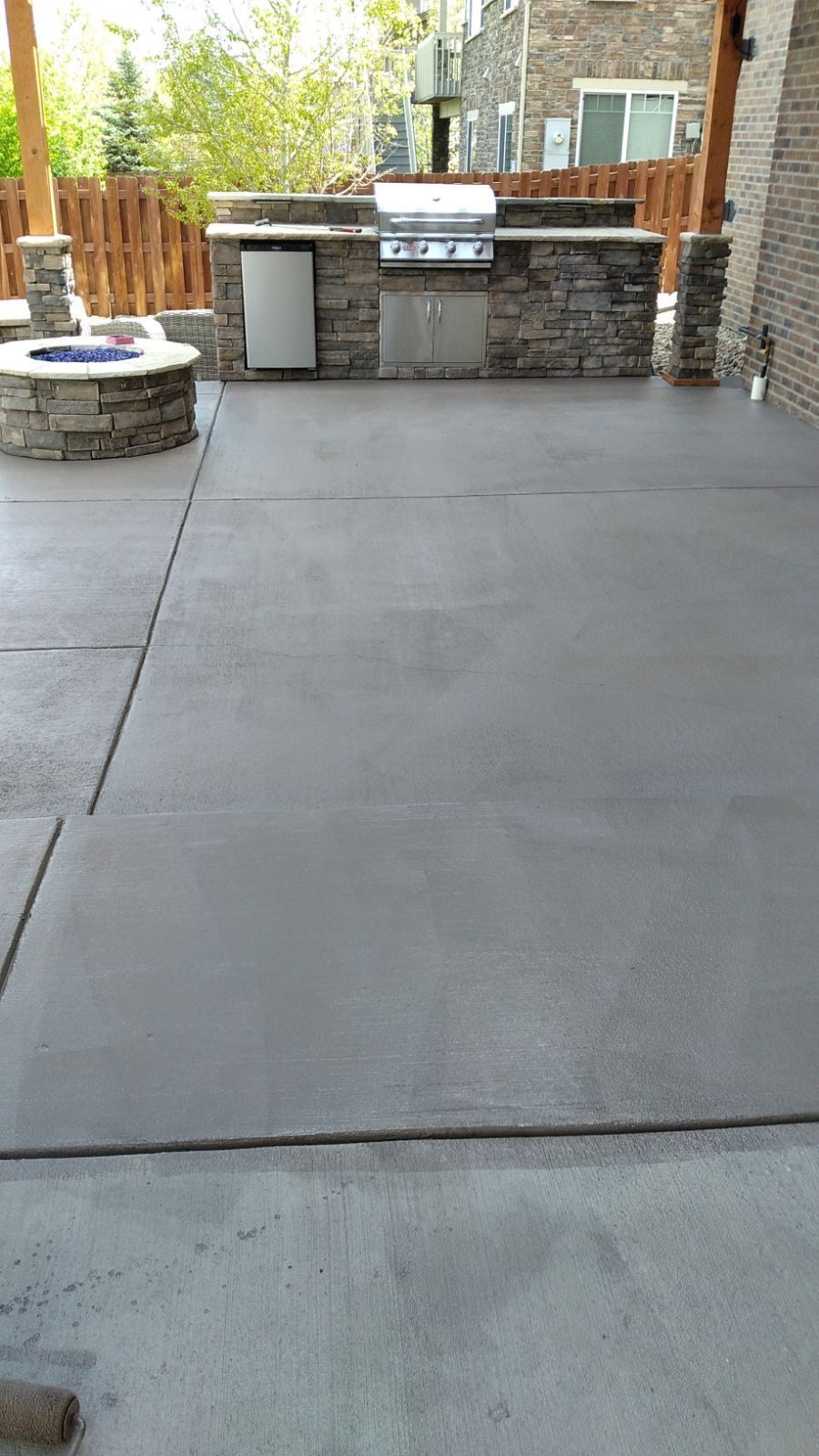 A concrete patio with a grill and a fire pit.
