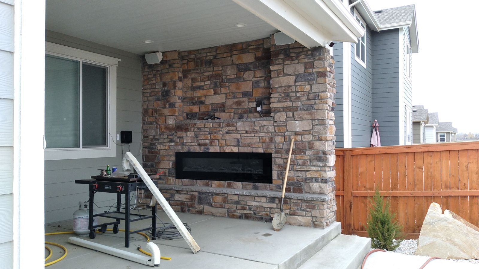 A brick fireplace is being built in the backyard of a house.