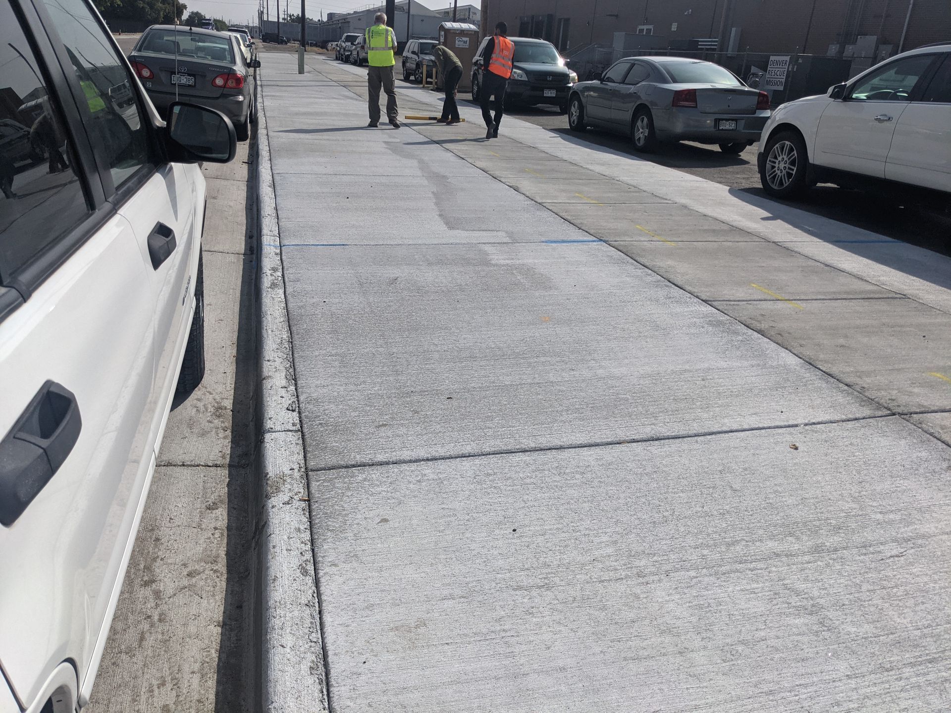 A white car is parked on the side of the road next to a sidewalk.
