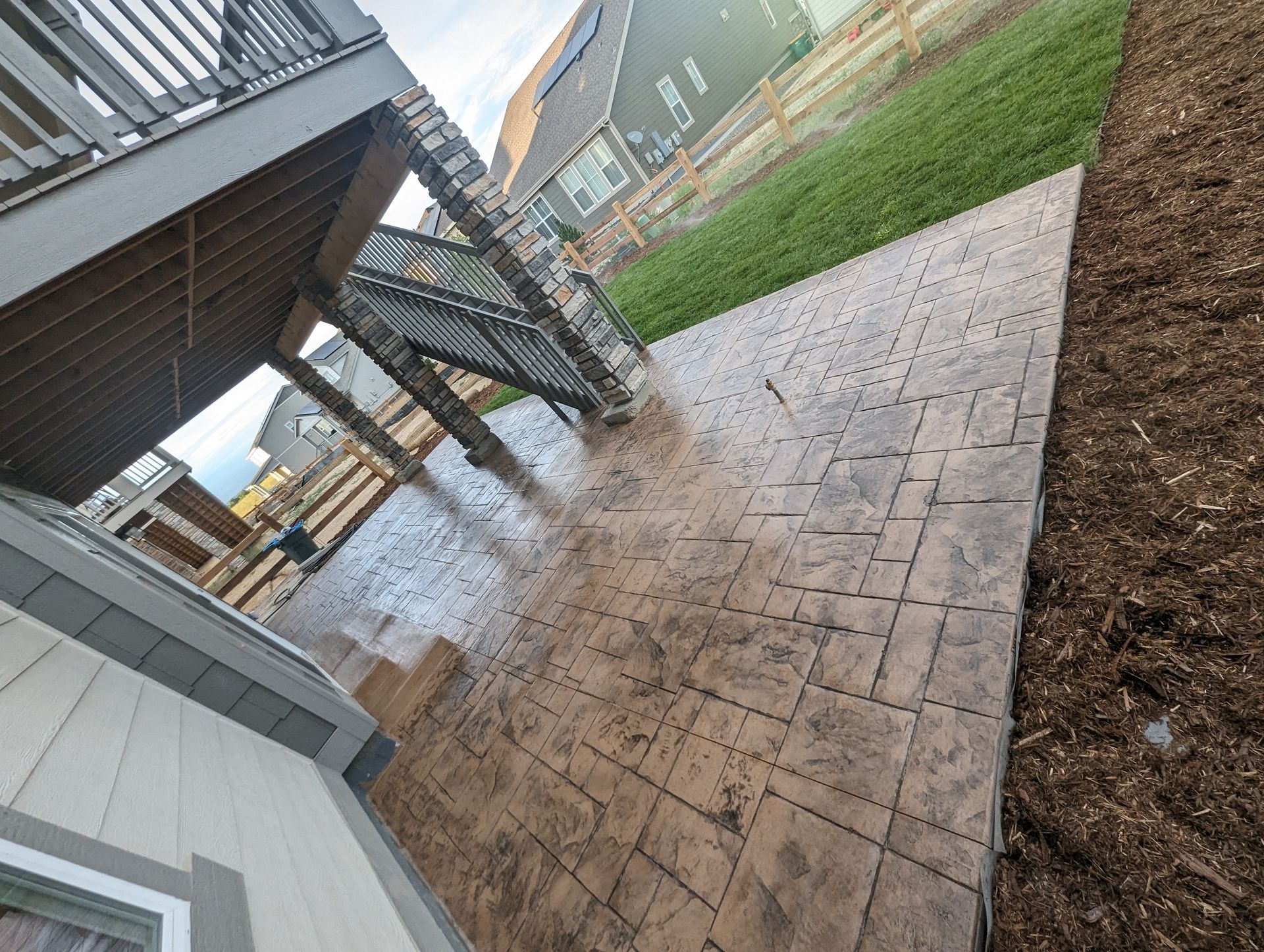 A patio with a deck and stairs in the backyard of a house.