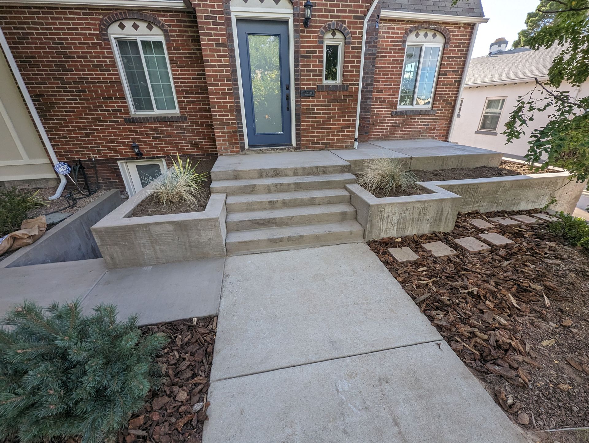 A brick house with a concrete walkway leading to the front door