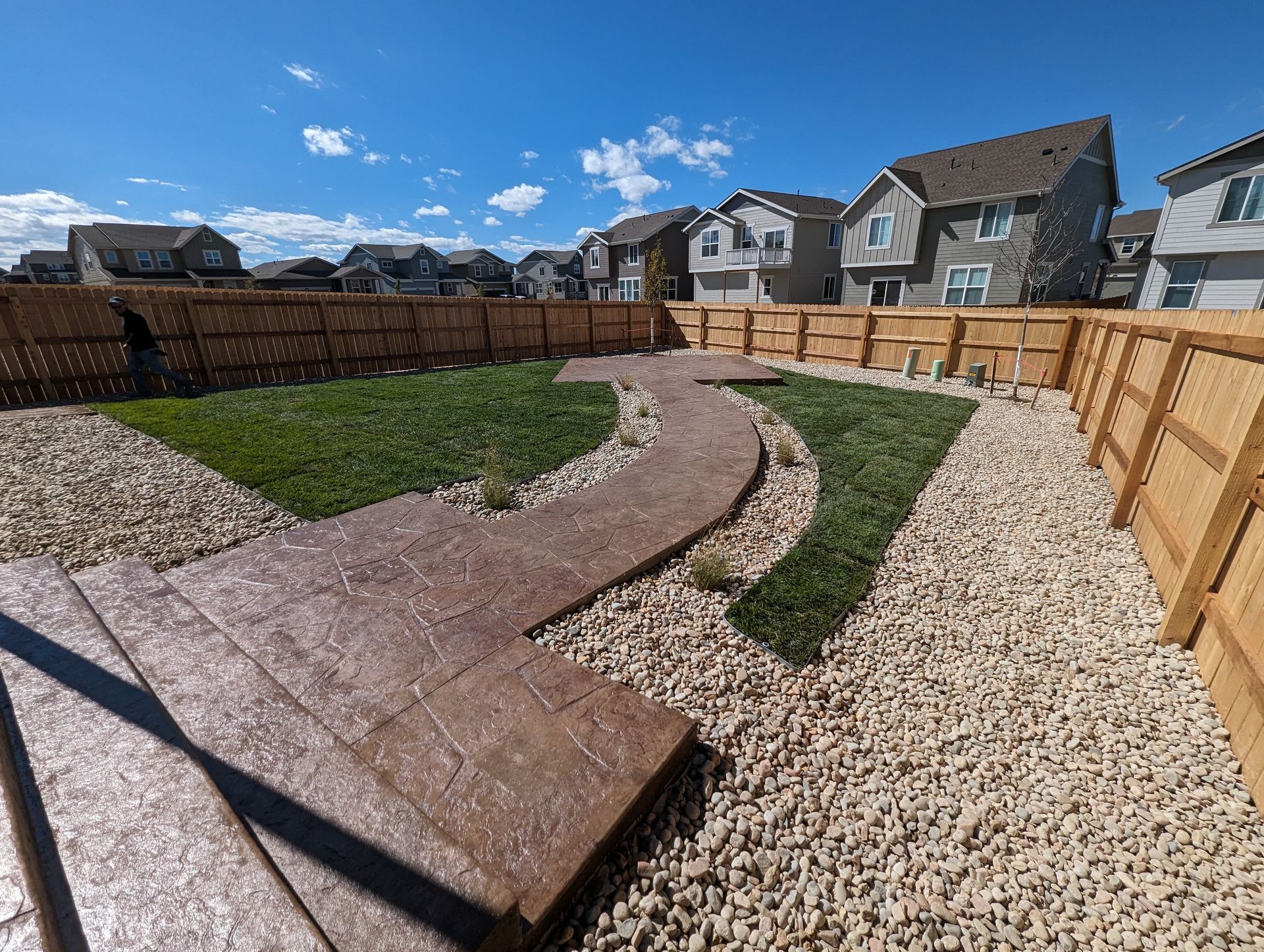 A backyard with a walkway and a wooden fence
