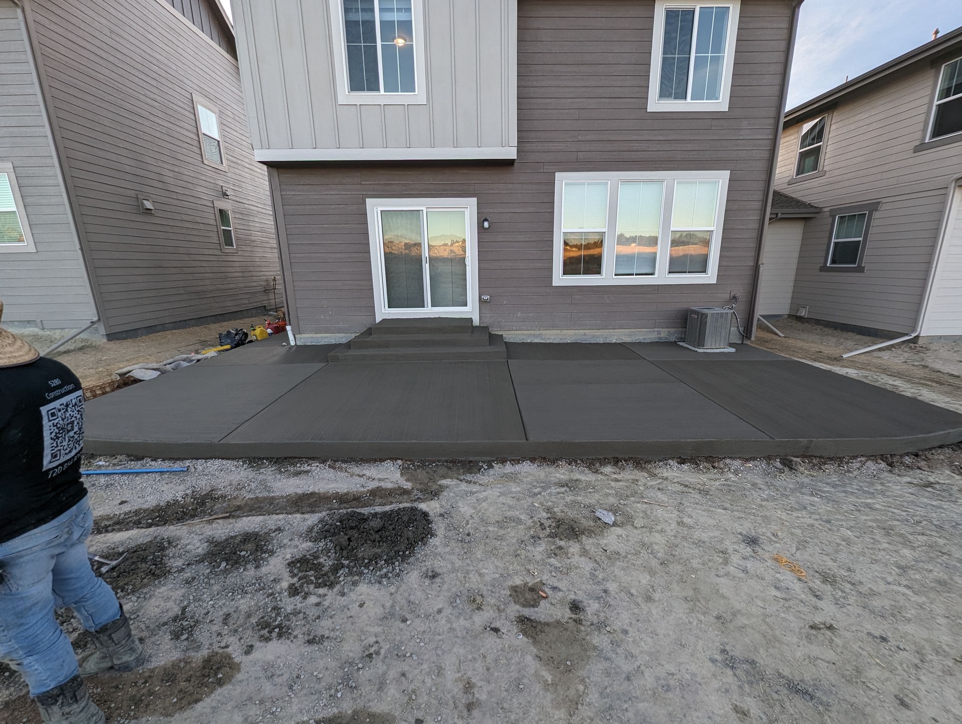 A man is working on a concrete patio in front of a house.