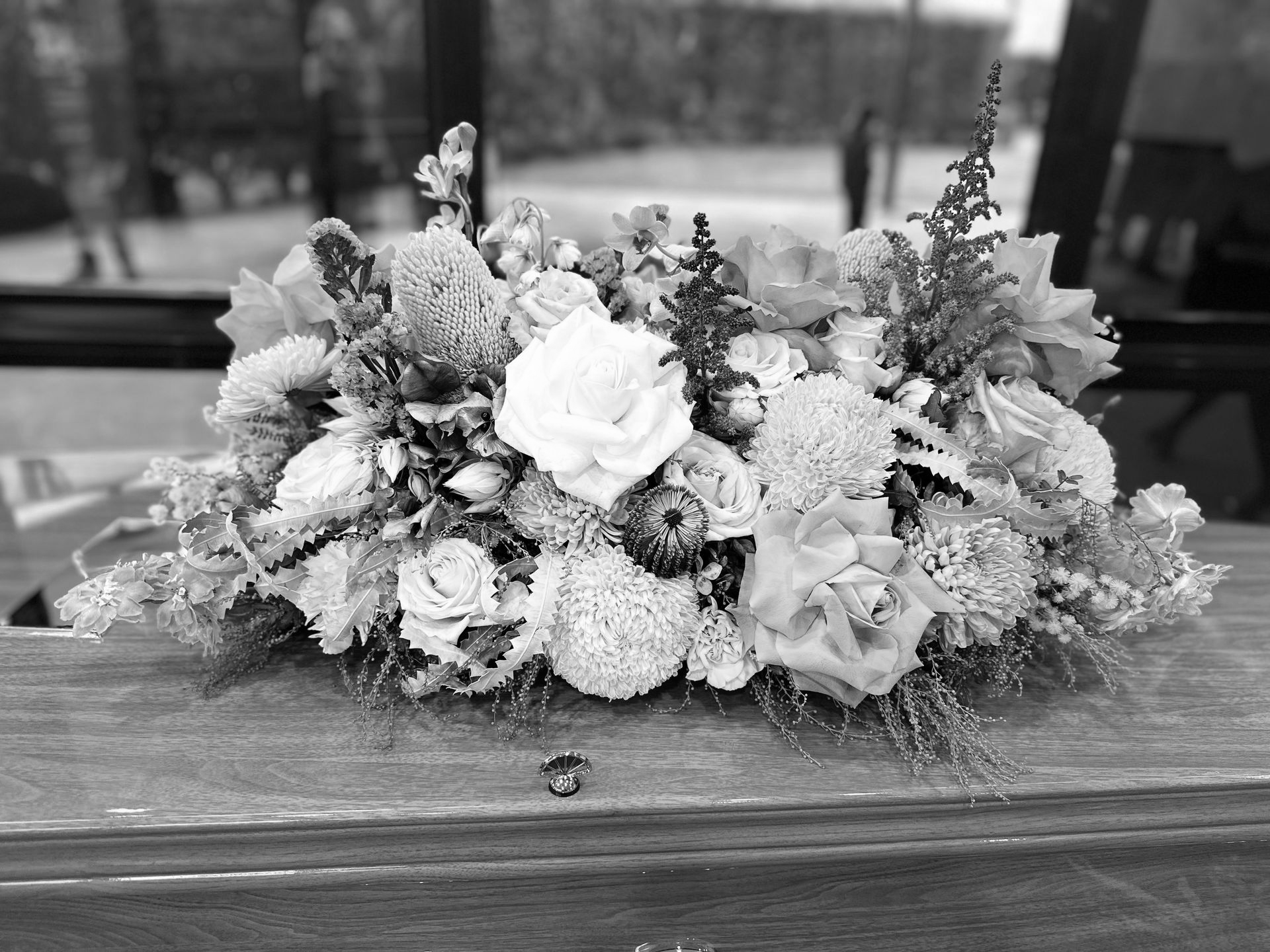 A floral arrangement on a wood surface; roses and other flowers in black and white.