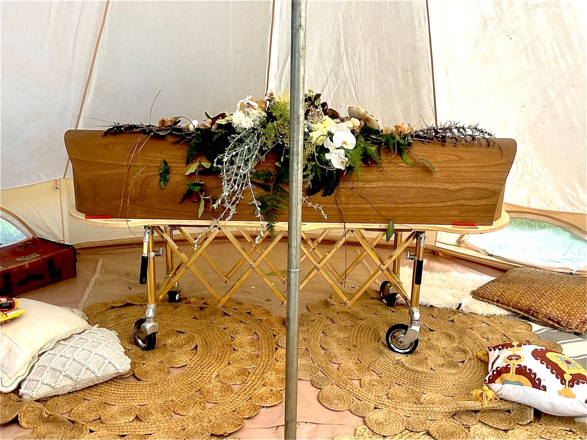 White coffin with floral arrangement, candles, and open hymnal.
