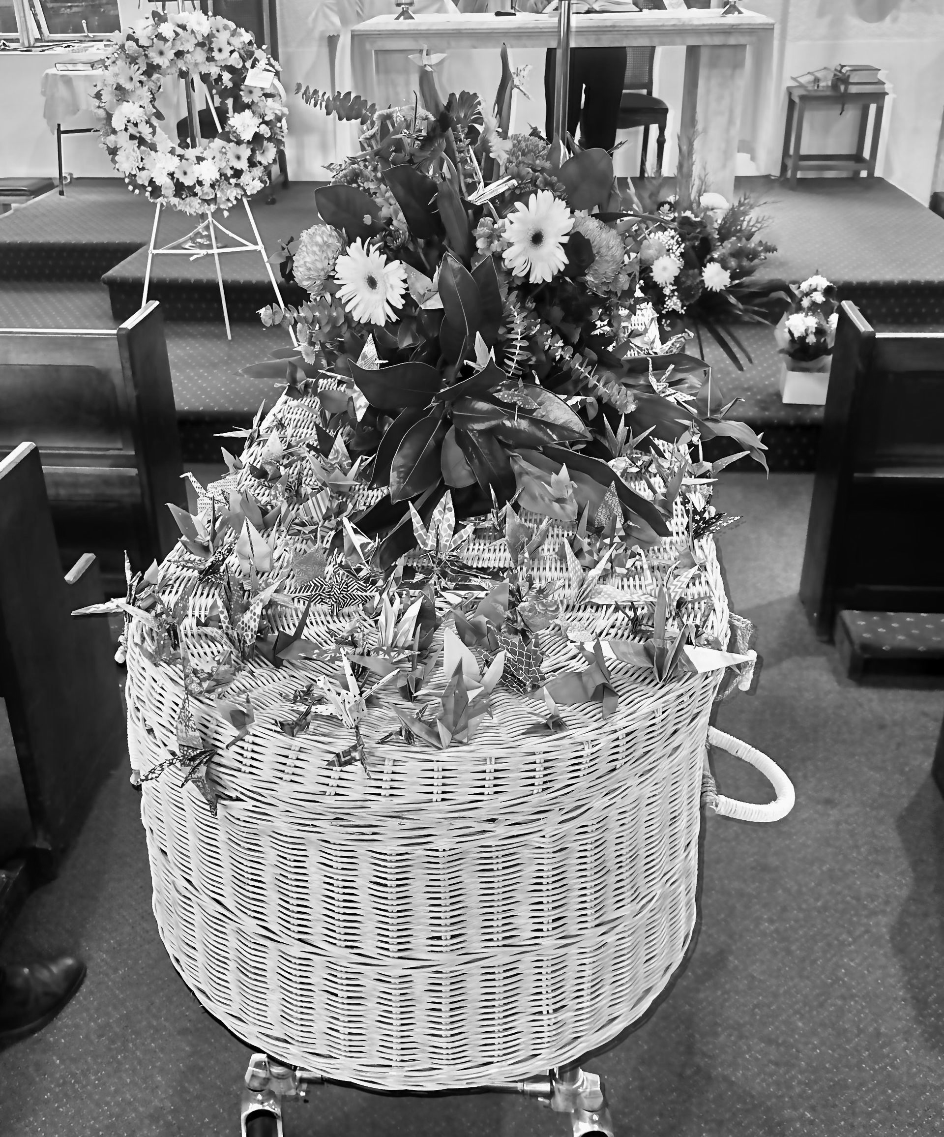 Wicker basket overflowing with flowers at a church service.