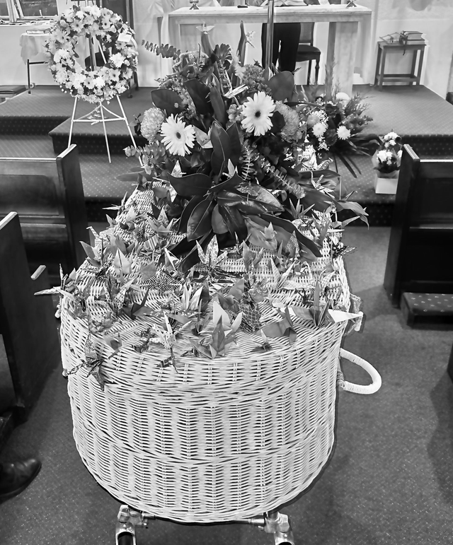 Wicker basket overflowing with flowers at a church service.