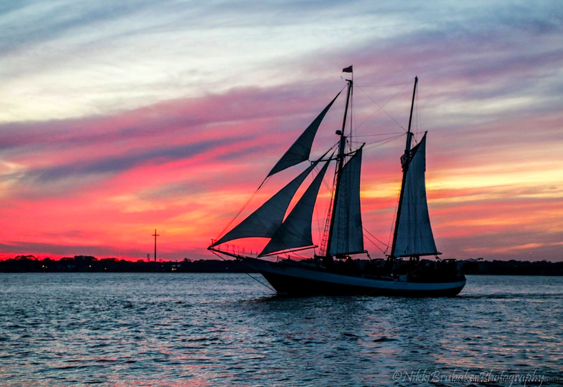 A sailboat is floating on the water at sunset