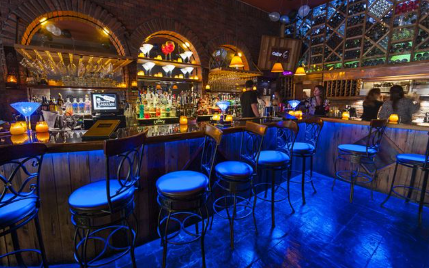 A bar with blue lights on the tables and chairs.