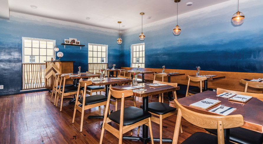 A restaurant with tables and chairs and a blue wall.