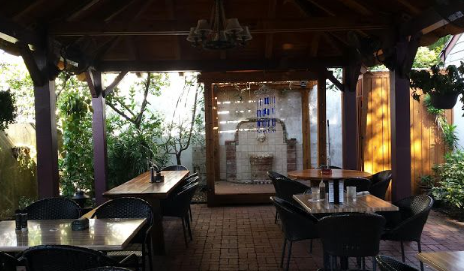 A restaurant with tables and chairs under a wooden roof.
