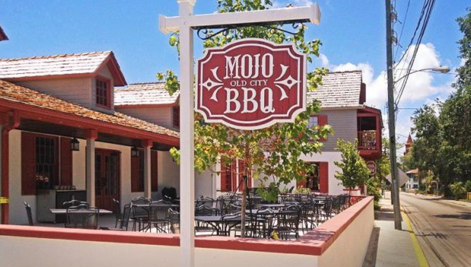 A sign for mojo bbq hangs outside of a restaurant