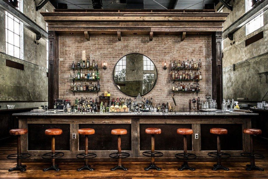 A long bar with stools and a brick wall.